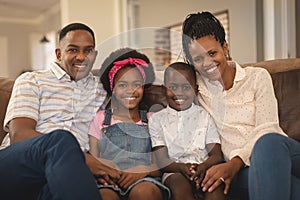 Happy African American family sitting on the sofa and looking at camera