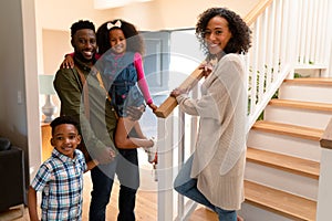 Happy african american family standing at stairs and looking at camera