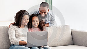 Happy african american family using laptop in living room