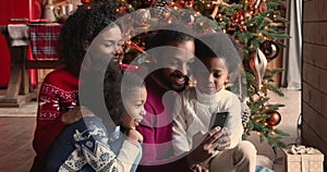 Happy african american family using smartphone, enjoying Christmas time together.