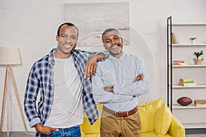happy african american father and adult son standing together and smiling at camera