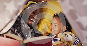 Happy african american father and daughter lying in tent and reading book