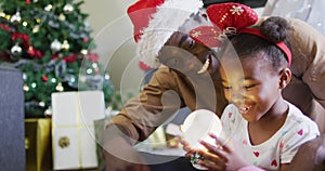 Happy african american father with daughter playing with snow globe