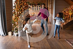 Happy African American father with kids dancing, celebrating Christmas together