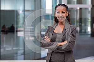 Happy African American female company leader CEO boss executive standing in front of company building