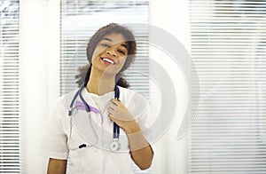 Happy african american female doctor physician wearing medical uniform with stethoscope around neck smiling at camera