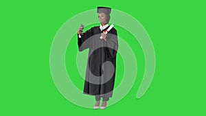 Happy African American female graduate holding diploma and making selfie on a Green Screen, Chroma Key.