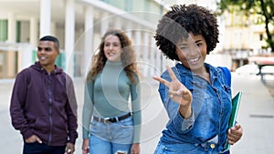 Happy african american female student with backpack and group of international students