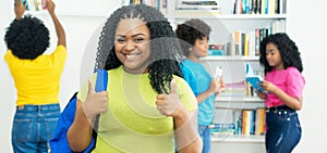 Happy african american female student showing thumbs up with group of college students