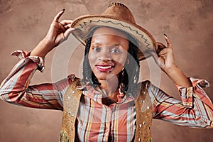 Happy african american girl cowboy with hat. brown background. portrait