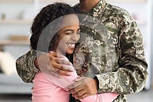 Happy african american girl hugging her mother soldier