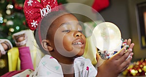 Happy african american girl playing with snow globe