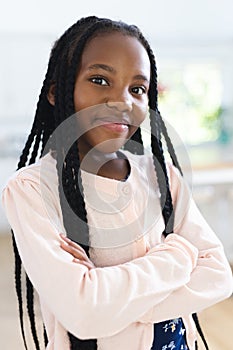 Happy african american girl standing with arms crossed at home, copy space