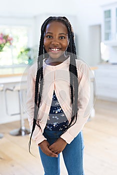 Happy african american girl standing and holding hands at home, copy space