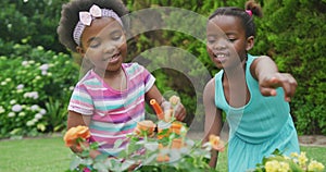 Happy african american girls watering plants and working in garden