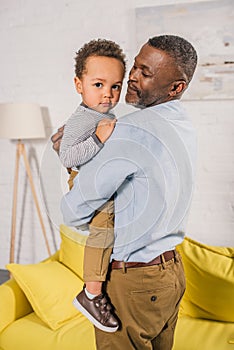 happy african american grandfather carrying adorable little grandchild