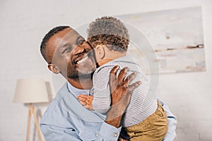 happy african american grandfather hugging adorable little grandchild