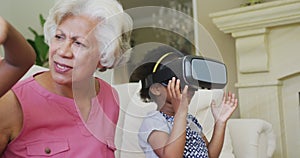 Happy african american grandmother with granddaughters using vr headset in living room