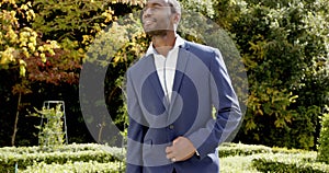 Happy african american groom walking and smiling at his wedding in sunny garden, slow motion