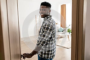 Happy African American Guy Entering Apartment Opening Door At Home