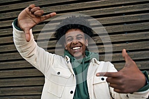Happy African American guy laughing taking selfie at wooden background. Portrait