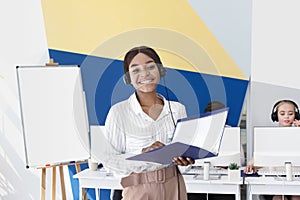 Happy African American helpdesk consultant in headset holding documents at modern call centre