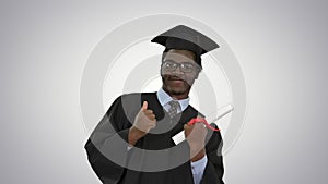 Happy african american male student in graduation robe posing with diploma for camera on gradient background.