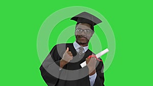 Happy african american male student in graduation robe posing with diploma for camera on a Green Screen, Chroma Key.