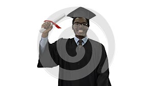 Happy african american male student in graduation robe walking towards camera waving his diploma on white background.