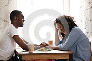 Happy African American man on date with attractive girlfriend in cafe