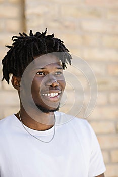 Happy African American man with dreadlocks walking down the street on a sunny day. Close-up portrait