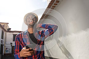 Happy african american man holding mobile phone outdoors