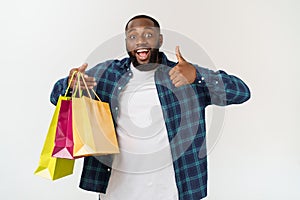 Happy african american man holding shopping bags on white background. Holidays concept photo