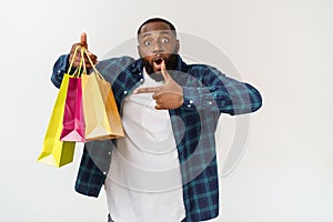 Happy african american man holding shopping bags on white background. Holidays concept