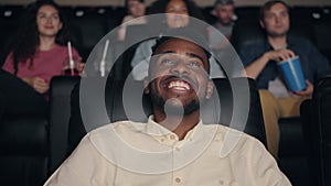 Happy African American man laughing in cinema watching funny comedy