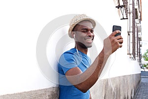 Happy african american man listening to music with mobile phone and earphones