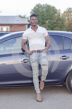 A happy African-American man near a car. Car sales and rentals
