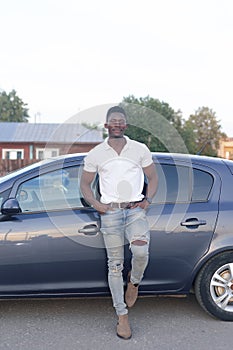 A happy African-American man near a car. Car sales and rentals