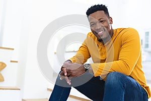 Happy african american man sitting on stairs and holding hands at home, copy space