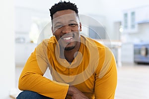 Happy african american man sitting on stairs at home, copy space