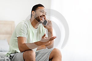Happy african american man talking on phone at home