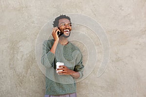 Happy african american man talking on smart phone with coffee