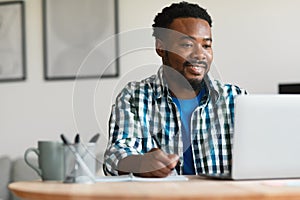 Happy African American Man Using Laptop Working Online At Home