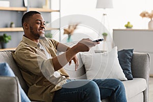 Happy African American Man Watching TV Switching Channels At Home