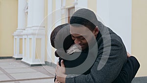 Happy african american man and woman hugging, meeting unexpectedly outdoors, slow motion