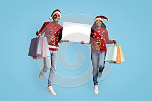 Happy african american man and woman shopaholics showing Christmas offer
