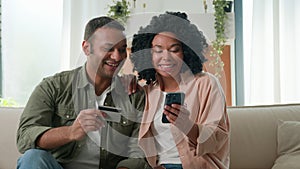 Happy African American married love couple man woman husband wife pay web store with credit card on mobile phone