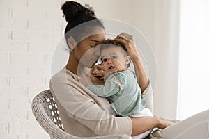 Happy African American mom embrace newborn baby daughter