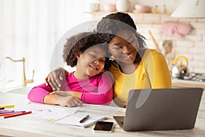 Happy African American Mom And Her Little Daughter Using Laptop In Kitchen