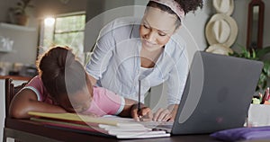 Happy african american mother and daughter using laptop, doing homework, slow motion, unaltered
